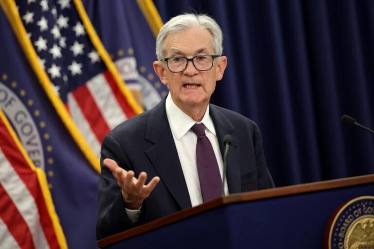 Ein fallender roter Kurs-Chart hinter einer physischen Bitcoin-Münze und dem Logo der Federal Reserve