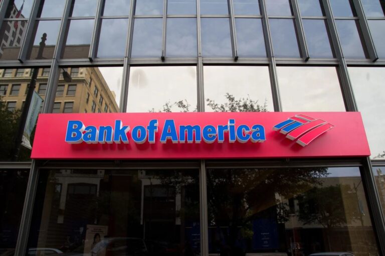 Das Logo der Bank of America im Hintergrund einer physischen Bitcoin-Münze und einem aufsteigenden Kurs-Chart