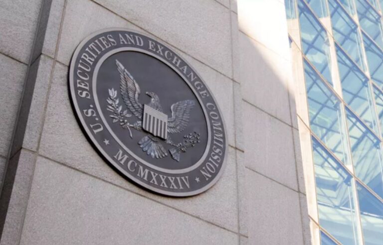 Das Logo der US-Börsenaufsicht SEC vor einem unscharfen Hintergrund mit digitalen Kursverläufen.