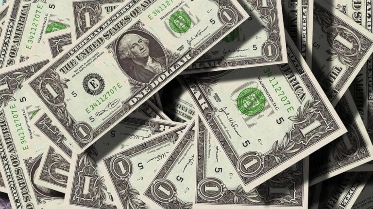 Ein geteilter Bildschirm zeigt einen fallenden Bitcoin-Chart und ein steigendes US-Dollar-Symbol