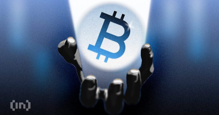 Nahaufnahme einer Bitcoin-Münze auf einem steigenden Kurs-Chart im Hintergrund