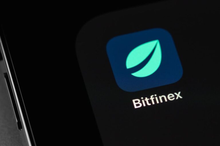 Ein roter fallender Kurs-Chart mit einer Bitcoin-Münze und dem Logo von Bitfinex
