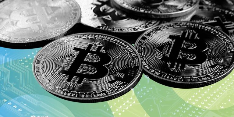 Eine physische Bitcoin-Münze vor einem digitalen, nach unten gerichteten Kurs-Chart