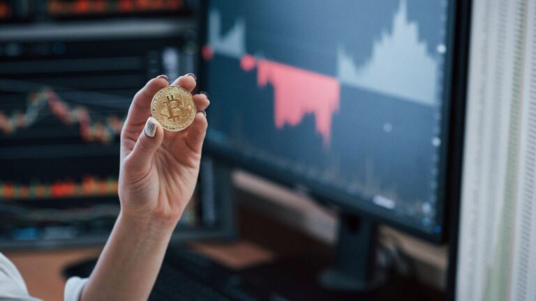 Ein fallender Kurs-Chart vor dem Logo der US-Bank JPMorgan und einer Bitcoin-Münze