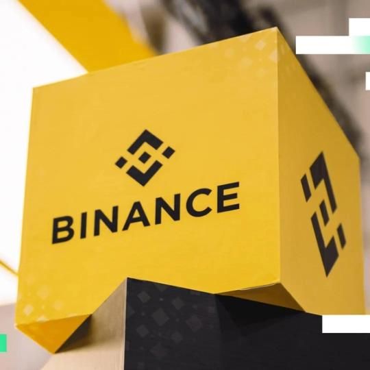 Bitcoin-Münzen mit dem Logo der Kryptobörse Binance auf einem digitalen Finanz-Hintergrund