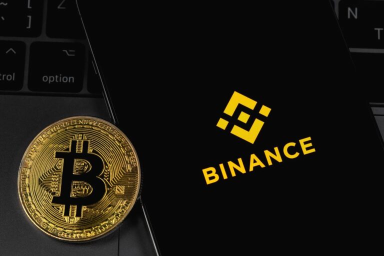 Physische Bitcoin-Münze neben den Logos von Tether und Binance vor einem Kurs-Chart
