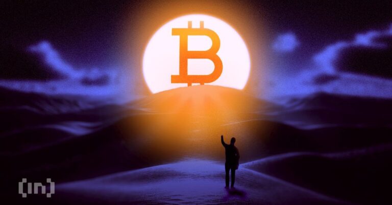 Nahaufnahme einer physischen Bitcoin-Münze vor einem roten absteigenden Kurs-Chart