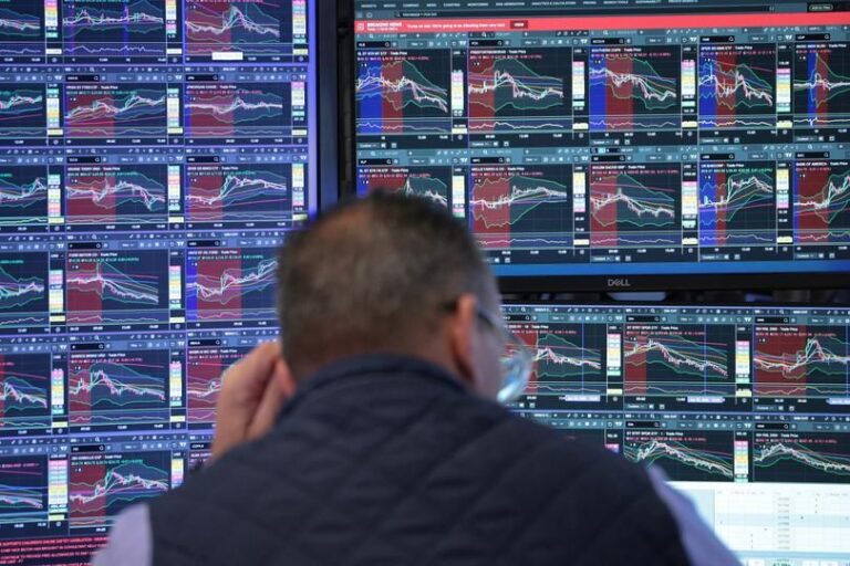 Ein aufsteigender Kurs-Chart auf einem Bildschirm hinter einer goldenen Bitcoin-Münze.