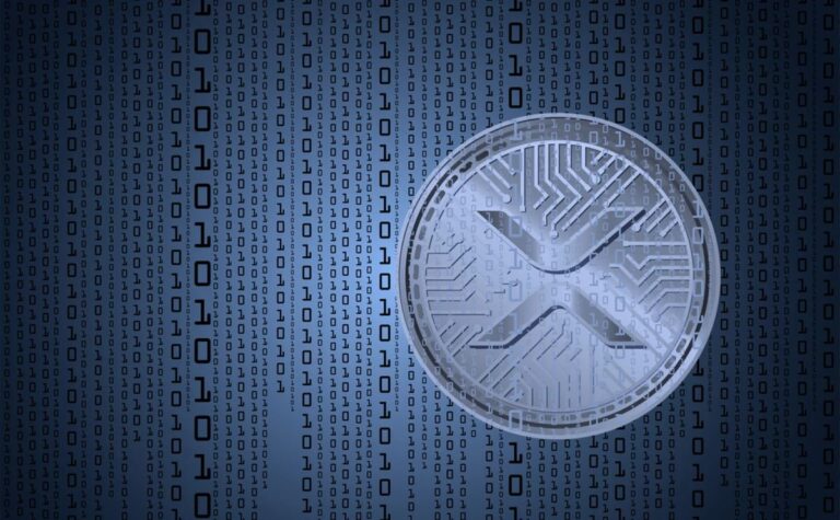 Nahaufnahme einer physischen XRP-Münze vor einem rot gefärbten digitalen Kurs-Chart