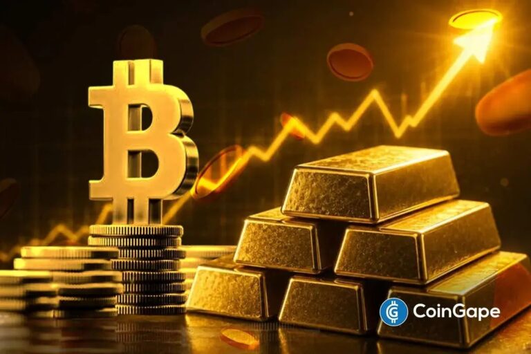 Eine physische Bitcoin-Münze liegt neben einem Goldbarren auf einem roten Kurs-Chart.