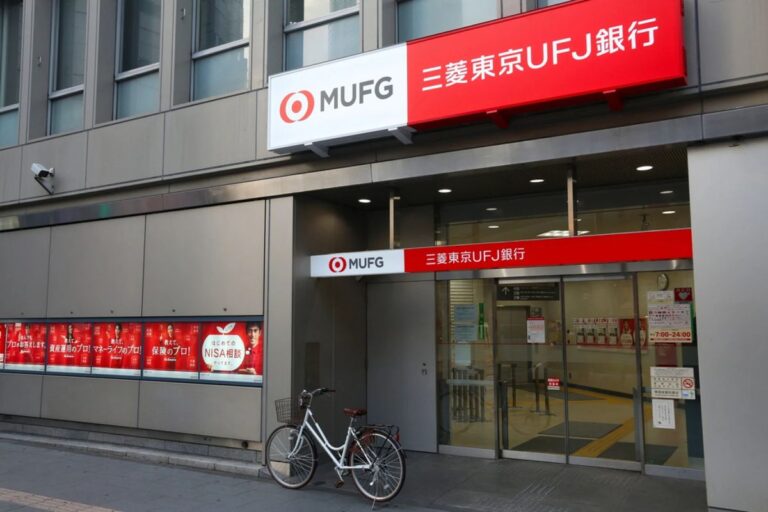 Das Firmenlogo von Mitsubishi UFJ neben dem Logo von MicroStrategy und einer Bitcoin-Münze