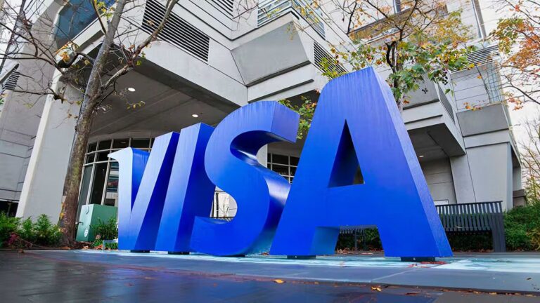 Visa-Logo auf einem Bildschirm neben einer digitalen Tether-Münze